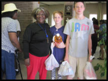 Two young volunteers help a client out with her groceries.