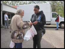 A volunteer helps a recipient with her groceries.