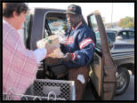A volunteer helps a recipient put food into his truck.