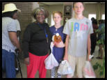 Two young volunteers help a client out with her groceries.